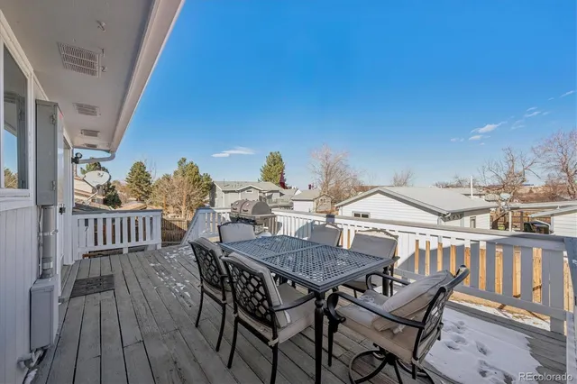 a view of a roof deck with table and chairs with wooden floor and fence