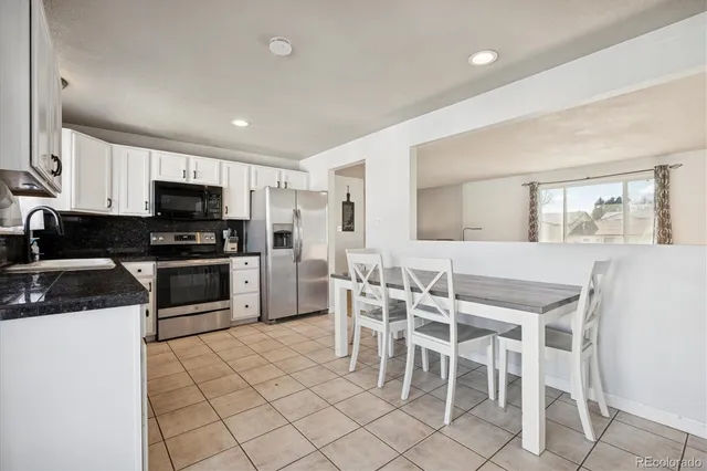 a kitchen with stainless steel appliances kitchen island granite countertop a stove a sink a dining table and chairs