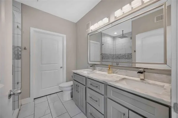 a bathroom with a granite countertop sink a toilet and a large mirror