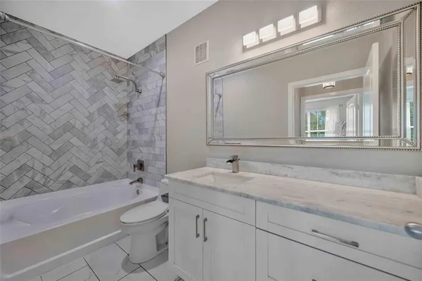 a bathroom with a granite countertop sink a toilet and bathtub