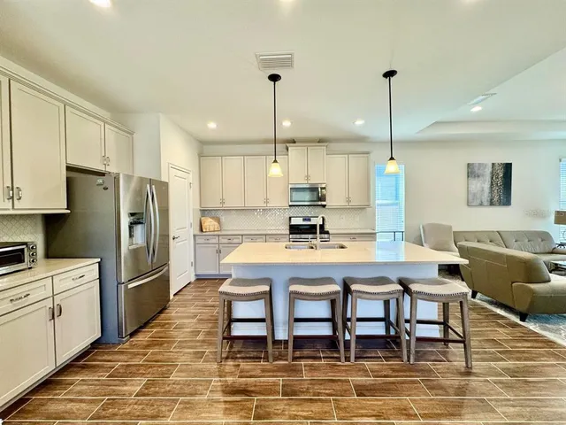 a kitchen with stainless steel appliances kitchen island granite countertop a table chairs microwave and sink