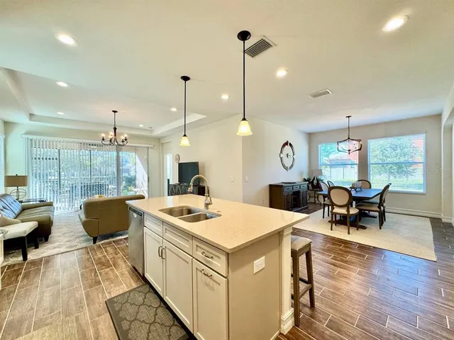 a kitchen with a stove a dining table chairs and couches with wooden floor