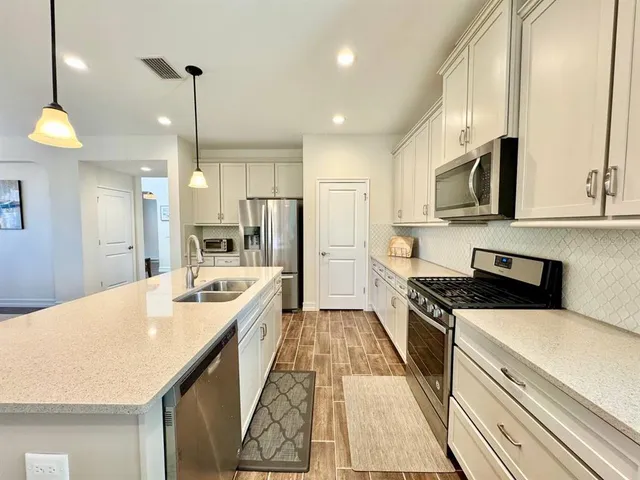 a open kitchen with stainless steel appliances granite countertop a sink a stove and a refrigerator