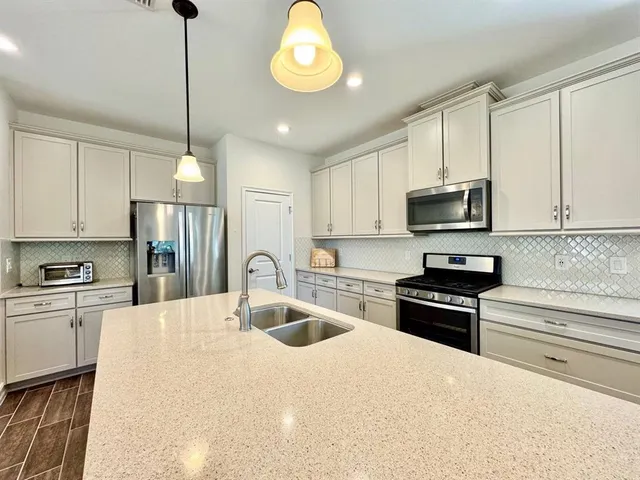 a kitchen with stainless steel appliances granite countertop a refrigerator a stove a sink and a microwave