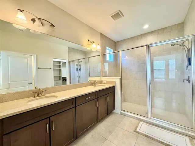 a bathroom with a double vanity sink mirror and shower