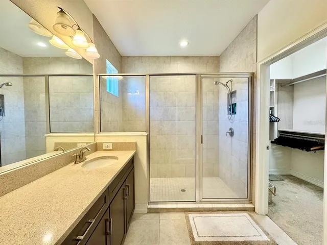 a bathroom with a granite countertop sink a mirror and shower
