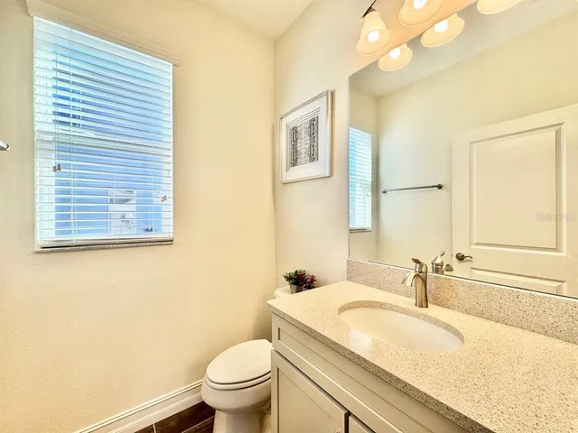 a bathroom with a granite countertop sink toilet and a mirror