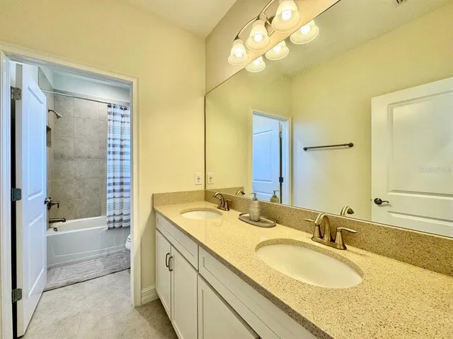 a bathroom with a granite countertop double vanity sink mirror and a bathtub