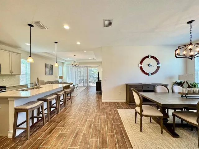 a dining hall with stainless steel appliances granite countertop a stove a sink a dining table and chairs with wooden floor