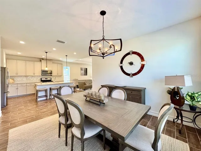 a view of a dining room and livingroom with furniture wooden floor a rug and a kitchen