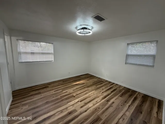 a view of a room with wooden floor and a ceiling fan