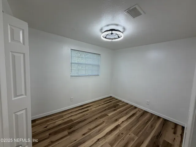 a view of empty room with wooden floor