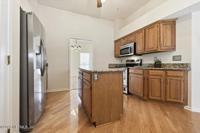 a kitchen with stainless steel appliances granite countertop a stove top oven a refrigerator a sink and dishwasher with wooden floor