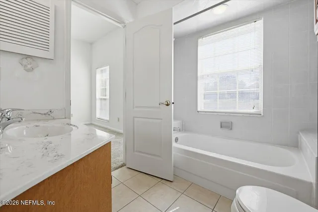 a bathroom with a granite countertop sink a toilet and bathtub