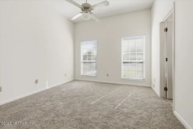 an empty room with windows and fan