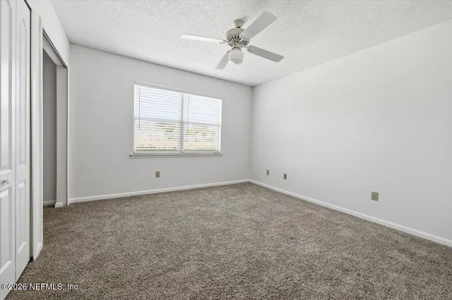 an empty room with windows and fan