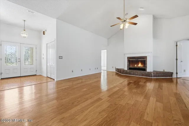 an empty room with wooden floor fireplace and windows