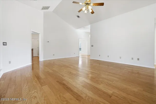 an empty room with wooden floor and chandelier fan