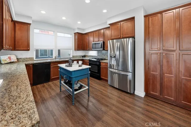 a kitchen with stainless steel appliances granite countertop a refrigerator stove microwave and sink