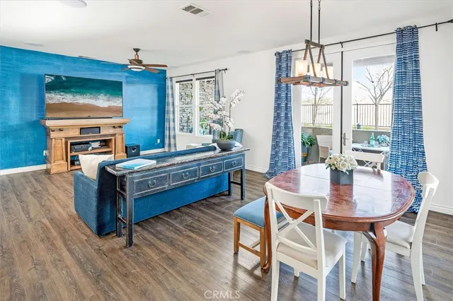 a living room with a dining table wooden floor and a chandelier