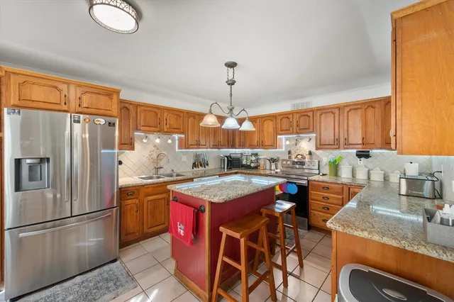 a kitchen with stainless steel appliances granite countertop wooden cabinets a dining table and chairs