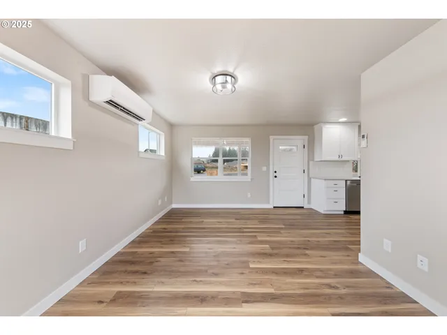 a view of an empty room with a window and wooden floor