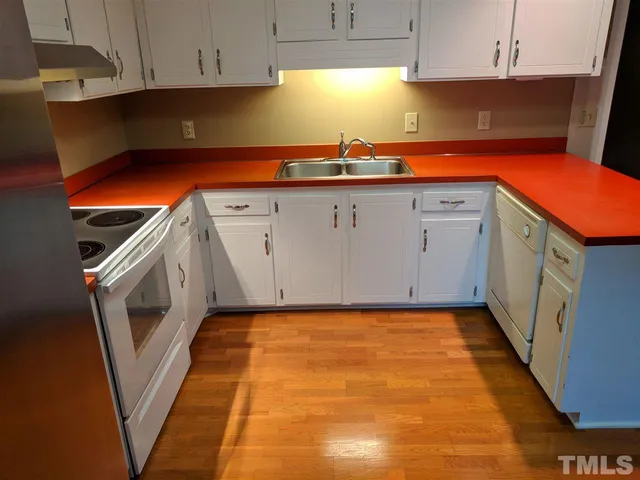 a kitchen with granite countertop a sink a stove top oven and cabinets