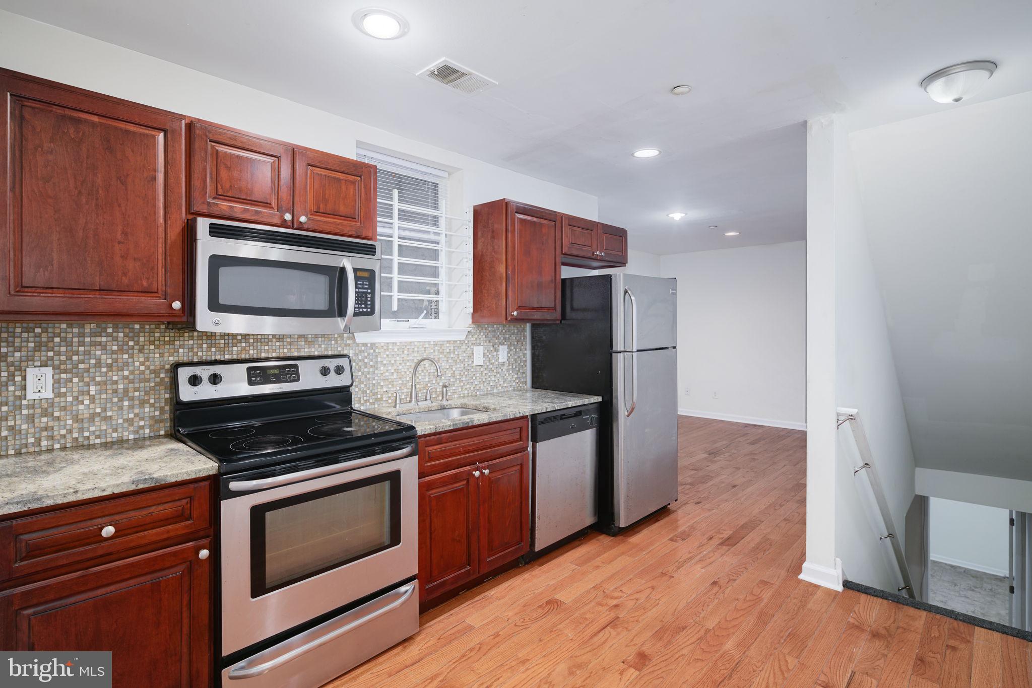 a kitchen with stainless steel appliances granite countertop wooden cabinets a stove a microwave and a refrigerator