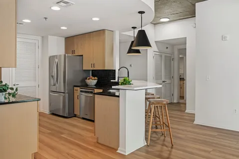 a kitchen with stainless steel appliances a refrigerator a sink a stove a microwave a center island and wooden floor