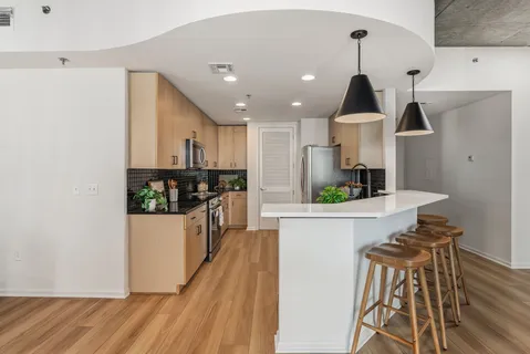 a kitchen with stainless steel appliances a refrigerator a stove a sink dishwasher and white cabinets with wooden floor