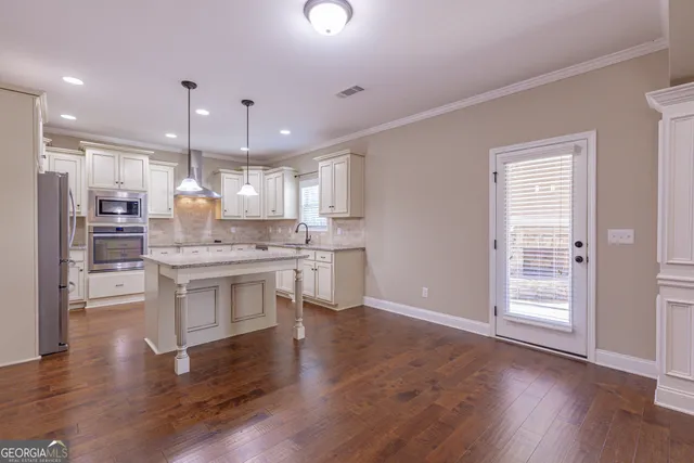 a kitchen with granite countertop white cabinets stainless steel appliances and a window