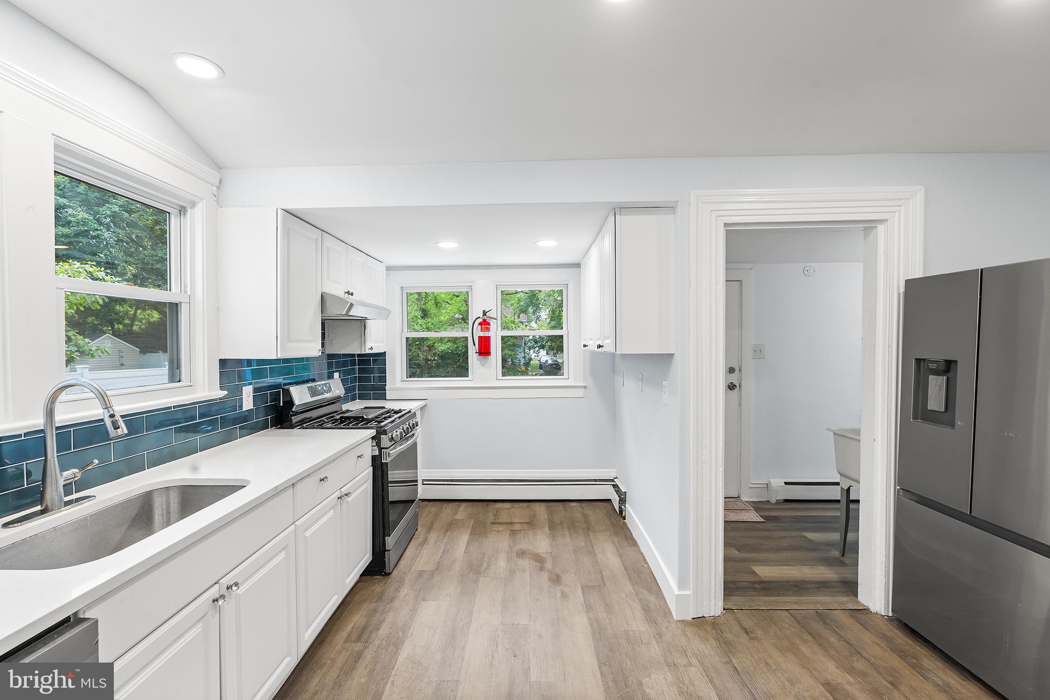 131 West Clinton Street Clayton, NJ 08312 - Photo 16 of 41 a kitchen with white cabinets and wooden floor