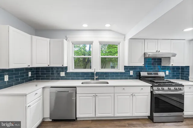 a kitchen with granite countertop a sink stainless steel appliances and white cabinets