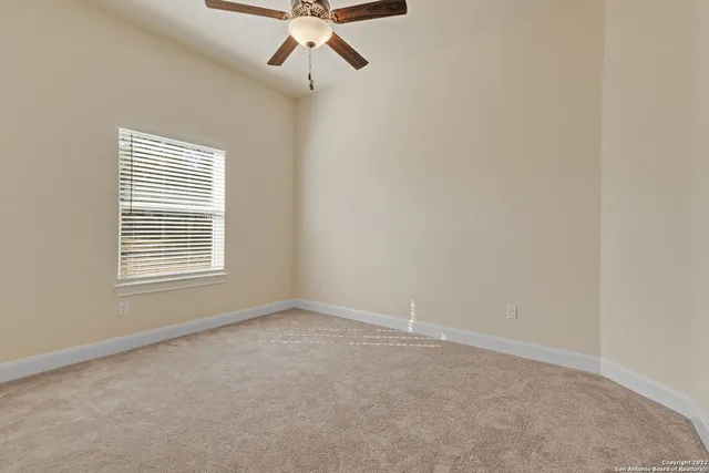 an empty room with a ceiling fan and a window