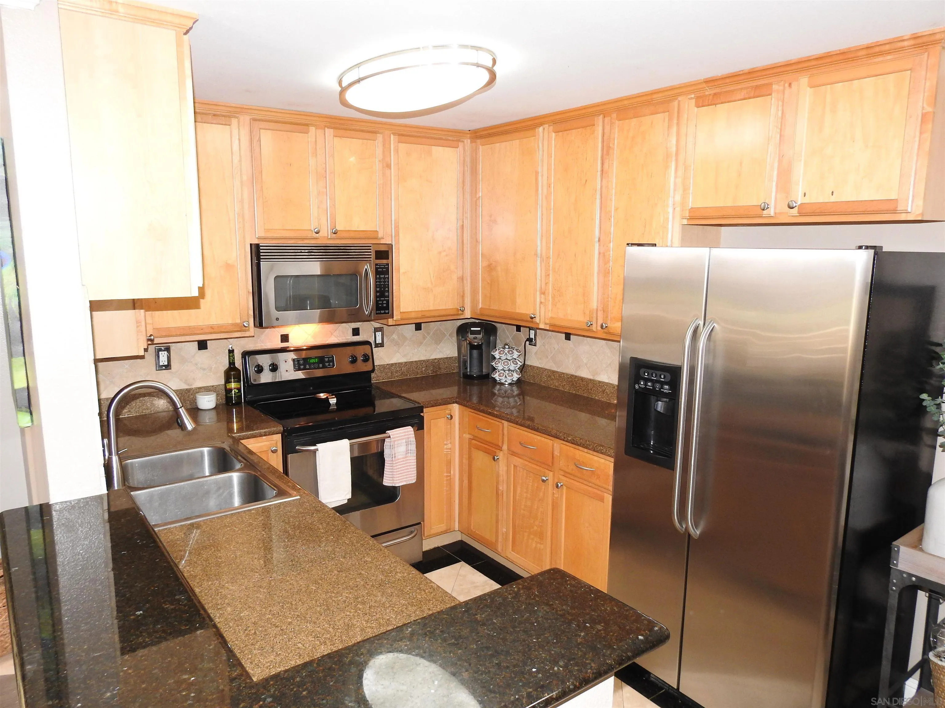 3515 Grove Street, Unit 108 Lemon Grove, CA 91945 - Photo 13 of 58 a kitchen with stainless steel appliances granite countertop a refrigerator a stove a sink dishwasher and a stove with the view of living room
