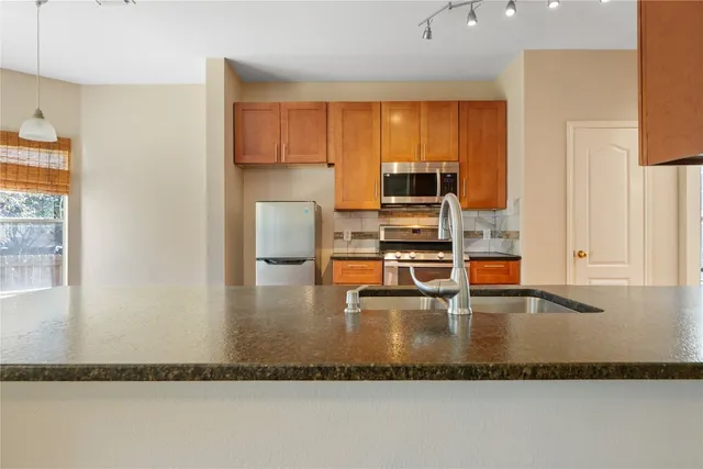 a kitchen with stainless steel appliances granite countertop a sink a stove and a refrigerator