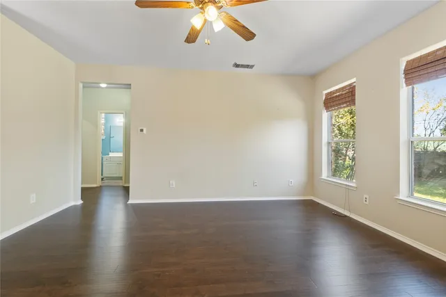 an empty room with wooden floor and windows