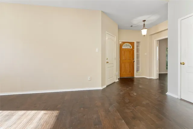 an empty room with wooden floor and bathroom view