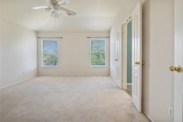 an empty room with windows and chandelier fan