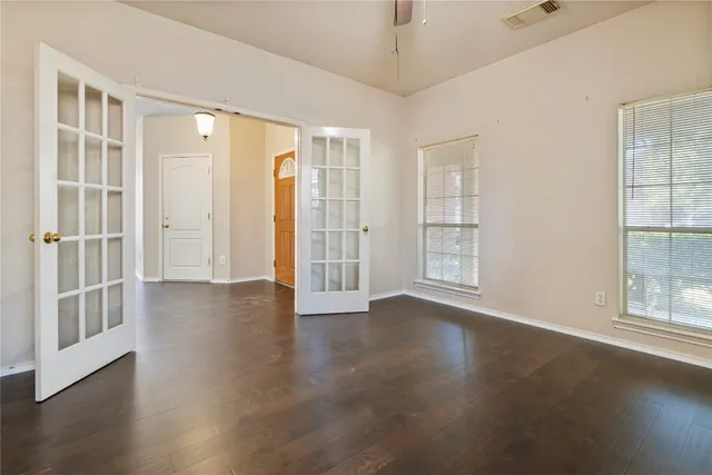 an empty room with wooden floor and windows