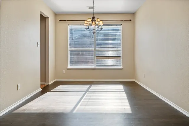 a view of an empty room with window and chandelier fan