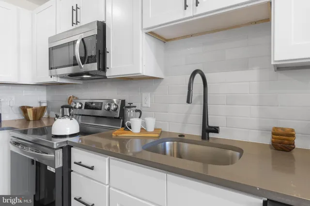 a kitchen with sink a microwave and cabinets