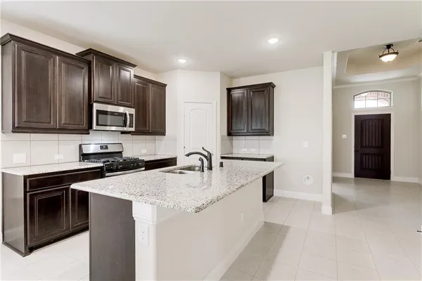 a kitchen with stainless steel appliances granite countertop a sink stove microwave and refrigerator