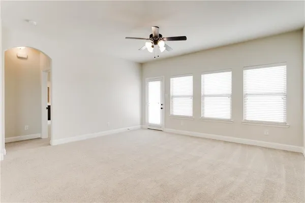 an empty room with windows and ceiling fan