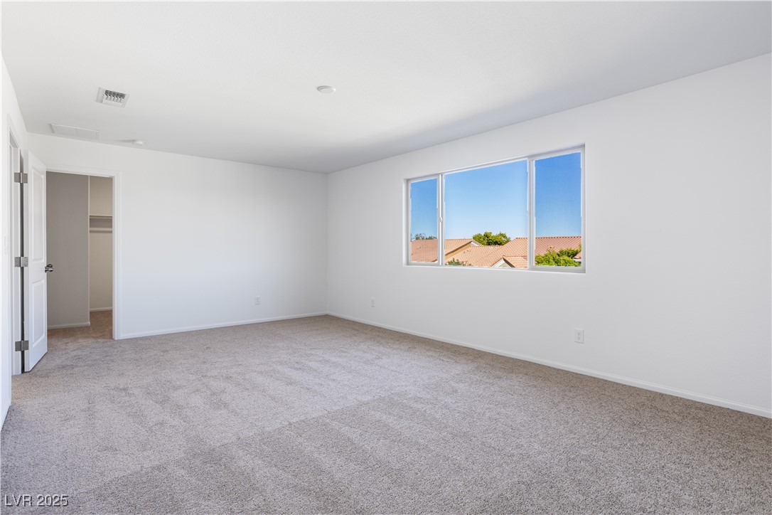 5662 Spring Trellis Street Las Vegas, NV 89113 - Photo 12 of 21 Unfurnished bedroom with a walk in closet and light colored carpet