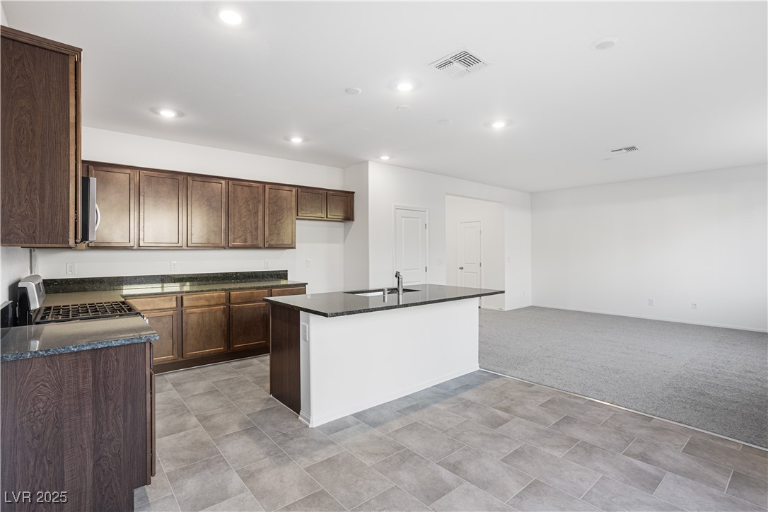 5662 Spring Trellis Street Las Vegas, NV 89113 - Photo 4 of 21 Kitchen with a kitchen island with sink, appliances with stainless steel finishes, light colored carpet, recessed lighting, and dark brown cabinetry