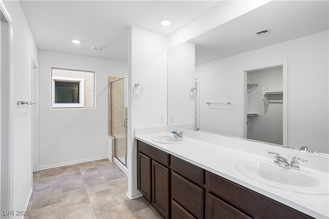 5662 Spring Trellis Street Las Vegas, NV 89113 - Photo 7 of 21 Bathroom featuring double vanity, a shower stall, a spacious closet, recessed lighting, and light tile patterned floors