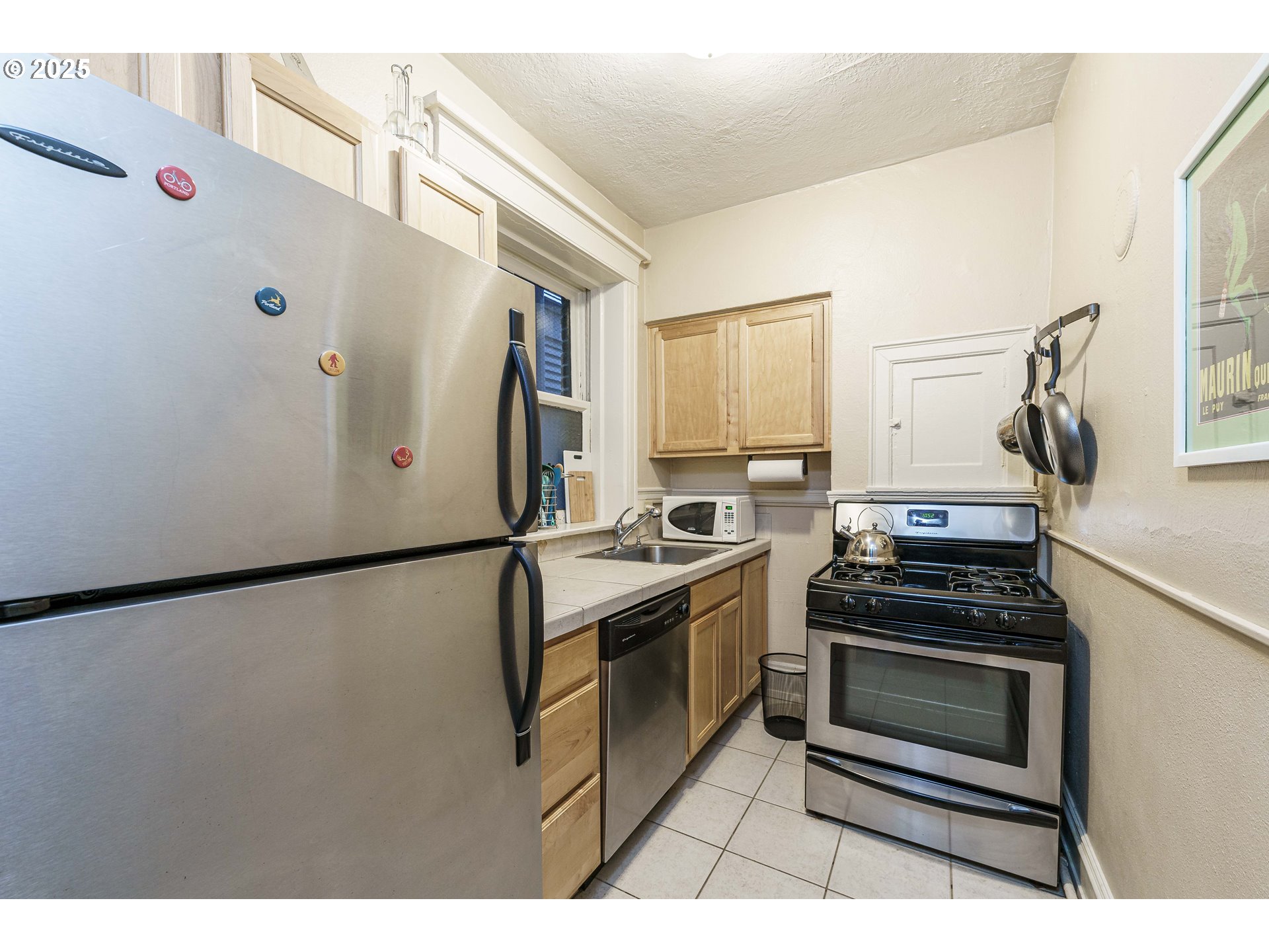 2109 Northwest Irving Street, Unit 114 Portland, OR 97210 - Photo 22 of 29 a kitchen with stainless steel appliances a stove a refrigerator and a window