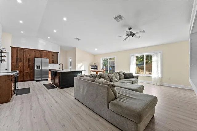 a living room with couches and kitchen view with wooden floor