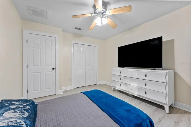 a living room with flat screen tv and a ceiling fan